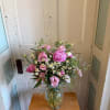 Pink flowers and white daisies arranged in a clear glass vase