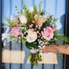 Handheld bouquet of pink and white roses with small white filler flowers