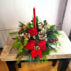 Christmas centerpiece with a red candle, poinsettia, and pinecones
