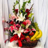 Basket arrangement of lilies, roses, and fruit with a red ribbon