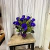 Blue rose bouquet in a glass vase with a purple ribbon