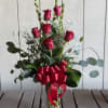 Red roses in a clear glass vase with a red ribbon
