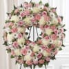 A soft, full circular wreath in pink, white, and green creates an