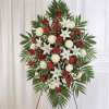 A formal red-and-white standing spray that commands attention with its dramatic palm-frond