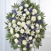 A large, oval standing spray in serene white and cool blue creates