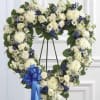 A large heart-shaped funeral wreath arranged on a metal easel, crafted in