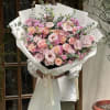 Large bouquet of pink roses and lisianthus wrapped in white paper