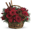 Red roses and gerbera daisies in a wicker basket with pinecones