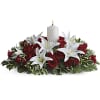 Red roses and white lilies arranged around a white candle