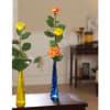 Two single-stem rose arrangements in tall colored glass vases