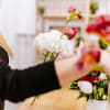 Person arranging red and white flowers in a vase
