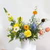 Mixed bouquet in a white vase with yellow, blue, and white flowers