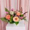 Pink and peach floral arrangement in a white vase