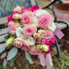 Pink roses, pink lisianthus, white ranunculus, and eucalyptus