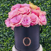 Pink roses arranged in a black hatbox with a gold butterfly topper