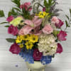 Mixed bouquet with pink roses, lilies, hydrangea, and yellow daisies in a vase