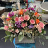 Mixed pink and orange flower arrangement in a wooden box