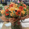 Orange roses and red gerbera daisies in a glass vase