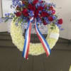 Red and blue floral wreath on an easel with ribbon streamers