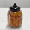 Amber textured glass jar with a black lid on a white surface