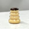 Beehive-shaped plastic jar filled with light golden contents and a dark brown lid on a light surface.