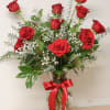 Red roses arranged in a clear glass vase with a red ribbon.