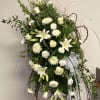 Tall white floral spray with lilies, roses, and ribbon on a twig frame