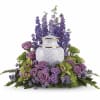Purple floral arrangement around a white urn-shaped vase