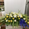 Low floral arrangement with white lilies, yellow roses, and blue flowers