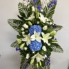 Tall floral standing spray with white lilies, blue hydrangeas, and purple flowers
