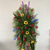 Tall standing floral spray with red roses, sunflowers, and purple spikes