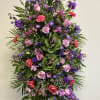 Tall standing spray of pink, purple, and red flowers on an easel