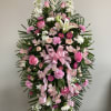 Pink and white funeral spray with roses, lilies, and ribbon