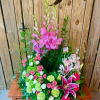 Tall pink floral arrangement with lilies and roses on a wooden table
