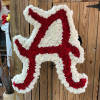 Red and white floral arrangement shaped like a cowboy boot on a stand