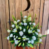 White lilies and carnations in a standing floral arrangement