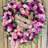 Heart-shaped floral wreath with pink and purple flowers and a ribbon