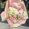 Pink and white bouquet of roses, hydrangeas, and lisianthus in pastel wrap