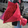 Large bouquet of red roses wrapped in bright pink paper