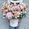 Large pink and white flower arrangement in a white hat box