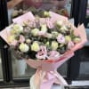Bouquet of pale pink and cream roses with pink blooms wrapped in pink paper