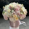Large pastel bouquet of roses, hydrangeas, and orchids in a pink hat box