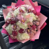 Pink and white bouquet with orchids and roses wrapped in pink paper
