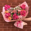Pink rose bouquet wrapped in pale pink paper with a ribbon