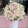 Large pastel bouquet of pink and white flowers in a tall white pedestal vase