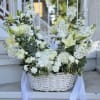 White floral basket arrangement with lilies, roses, and ribbon