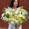 Large bouquet of pale green and white flowers in a glass vase