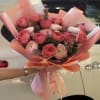 Pink rose and ranunculus bouquet wrapped in peach paper