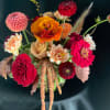 Mixed bouquet of bright dahlias and roses in a glass vase