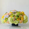 Low floral arrangement with roses, hydrangeas, and orchids in a black vase